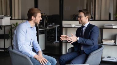 Gülümseyen erkek meslektaşlar ofiste konuşarak eğleniyor.