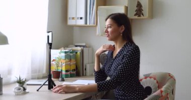 Kadın vlogger yeni video günlüğü kullanımı akıllı telefon kayıt masasında oturuyor