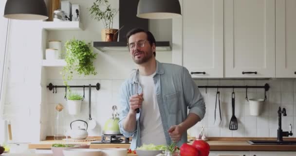 El hombre usa utensilio de cocina como micrófono cantando bailando mientras cocina — Vídeos de Stock