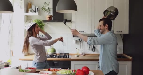 No casal de cozinha se divertindo segurando utensílios de cozinha e luta — Vídeo de Stock