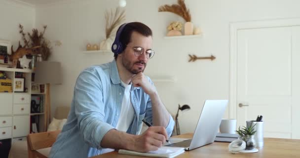 男人戴耳机，用笔记本电脑听音频学习语言 — 图库视频影像