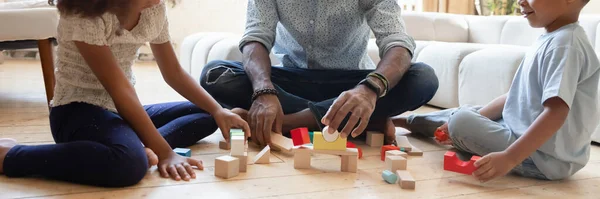 Banner view of biracial dad with kids play with bricks