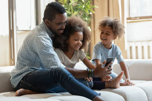 Heureux père biracial et les enfants utilisant un téléphone portable ensemble — Photo