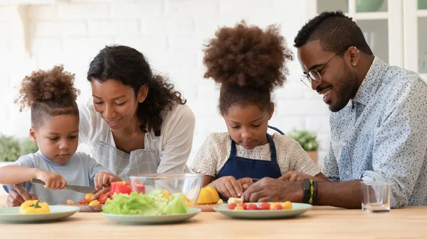 Amantes padres biraciales enseñan a los niños a cocinar en la cocina —  Fotos de Stock