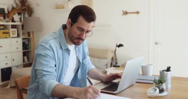 Telekomünikasyon çalışanı masa başında oturup bilgisayar ve kağıtlar üzerinde çalışıyor.