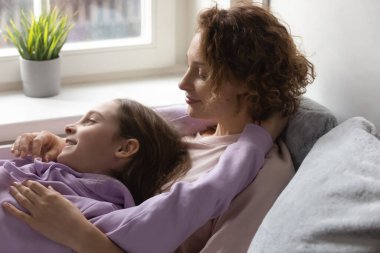 Mutlu anne ve genç kız yatakta dinleniyor.