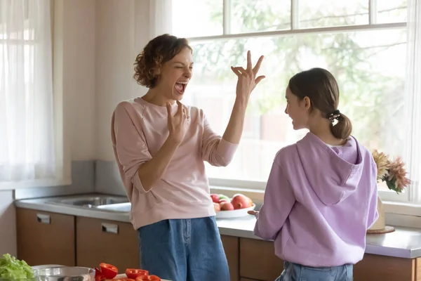 Веселая мать и дочь-подросток веселятся на современной кухне — стоковое фото