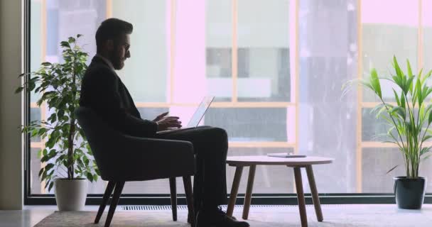 Fókuszált arab üzletember laptoppal ül irodai széken — Stock videók