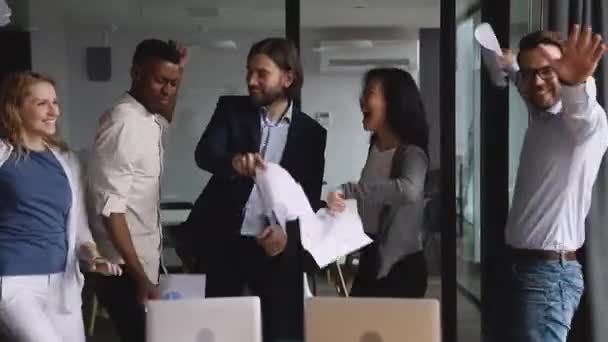 Счастливая многонациональная команда бизнесменов танцует, швыряя бумаги в офис — стоковое видео