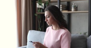 Hintli kadın akıllı telefon kullanarak kanepede oturuyor. Mesafe iletişiminin tadını çıkar.