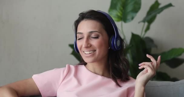 Donna indiana rilassante sul divano indossare cuffie ascolta musica — Video Stock