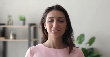 Kapalı alanda durup gülümseyen kameraya bakan Hintli kadının portresi.