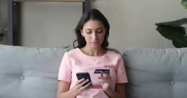 Elinde kredi kartı ve akıllı telefon ile internet üzerinden alım yapan Hintli bir kadın.