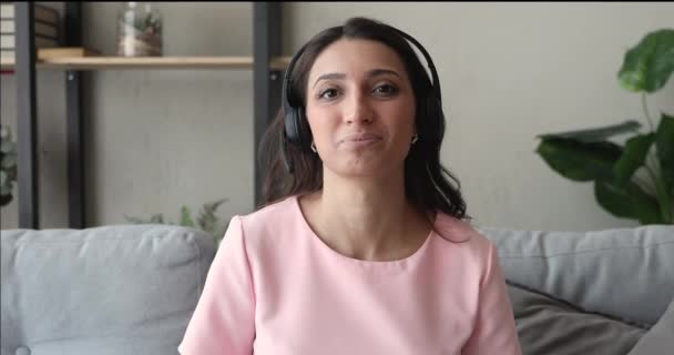 Indische Frau im Kopfhörer schaut in Kamera, die per Videotelefon spricht — Stockvideo