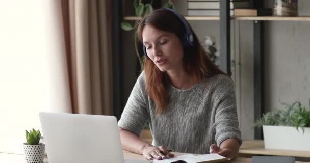 Женщина в наушниках учится с помощью ноутбука и приложения для видеозвонков — стоковое видео