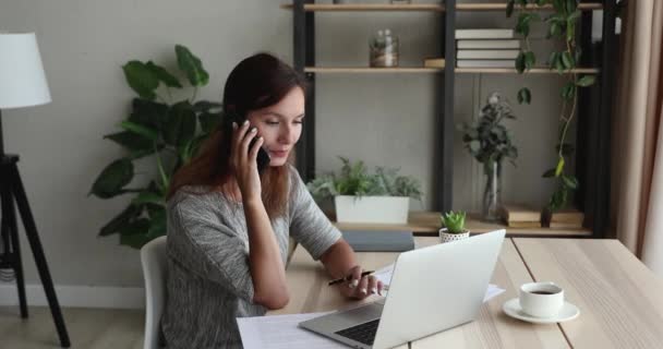Empresaria usando portátil escribir notas hablar por teléfono al cliente — Vídeos de Stock