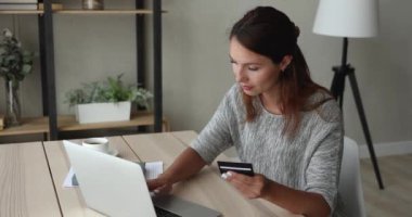 Evde oturan bir kadın internet üzerinden kredi kartı kullanıyor.