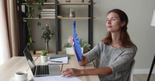 Mujer sentada en el lugar de trabajo usa ventilador enfriándose — Vídeos de Stock
