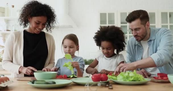 Famille multiraciale souriante impliquée dans la cuisine avec de petits enfants diversifiés. — Video