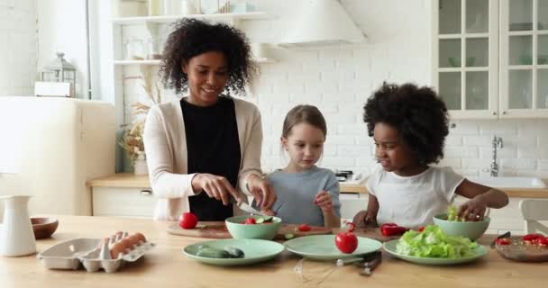 Afro-Amerikan annesi yemek pişirmeyi öğretiyor. Çok ırklı küçük kızlar.. — Stok video