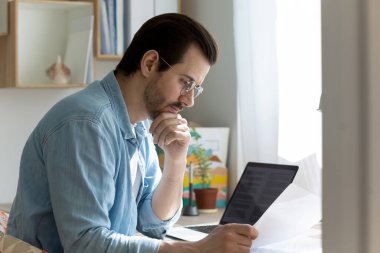 Düşünceli bir adam evde posta mektubu okurken düşünüyor.