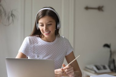 Evde dizüstü bilgisayarda çalışan gülümseyen kız öğrenci.