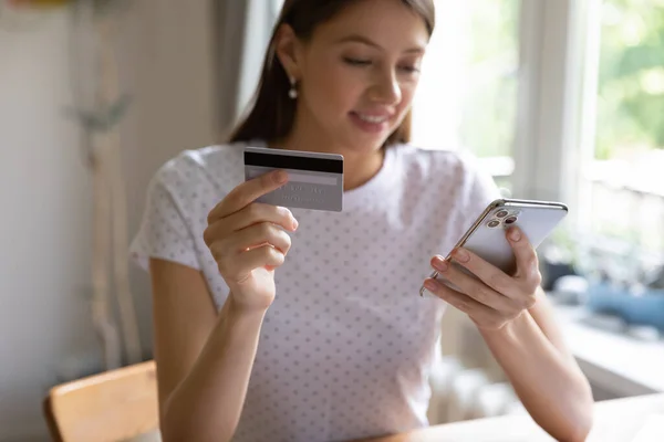 Ung kvinna gör betalning med kreditkort på mobiltelefon — Stockfoto