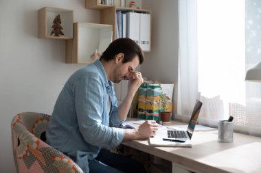 Yorgun adam, bulanık görme yüzünden gözlüğünü çıkar.