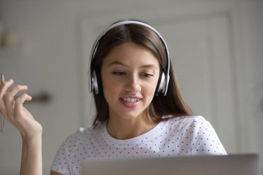 Kulaklık takan milenyum kızı dizüstü bilgisayarda giyer.