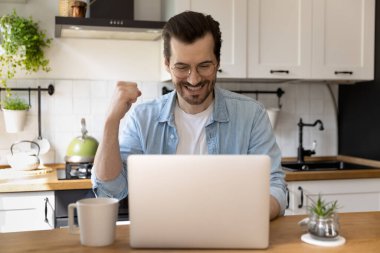 Mutlu genç adam dizüstü bilgisayardaki iyi haberlerle heyecanlandı.