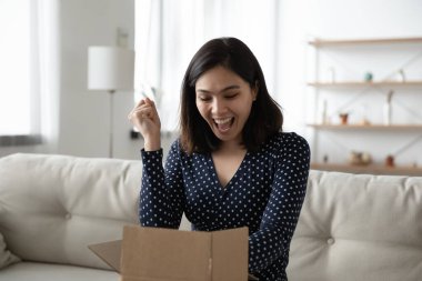 Heyecanlı Asyalı bayan müşteri çevrimiçi sipariş paketini açıyor