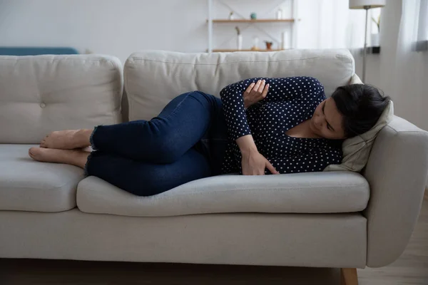 Upset young Asian woman lying on sofa at home suffering — Stock Photo, Image