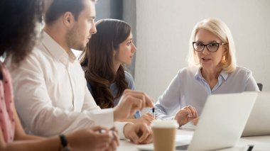 Çeşitli çalışanlar toplantıda ciddi bir olgun takım liderini dinliyor.