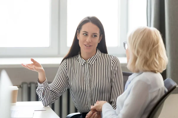 Молода бізнес-леді розмовляє зі зрілим колегою під час перерви в офісі — стокове фото