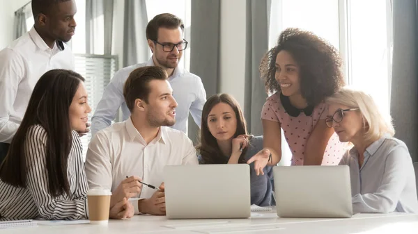 Equipo diverso de los empleados discutiendo el proyecto en línea, usando el ordenador portátil en reunión — Foto de Stock