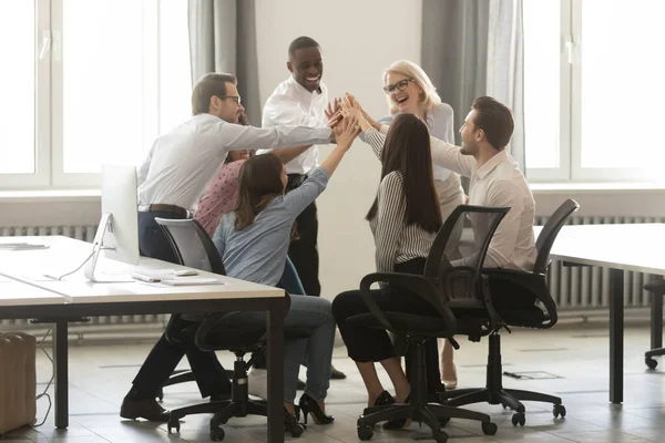 Happy diverse employees giving high five at business briefing