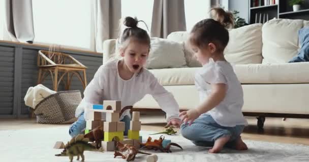 Twee kleine kleuterschoolkinderen spelen speelgoed in de woonkamer. — Stockvideo