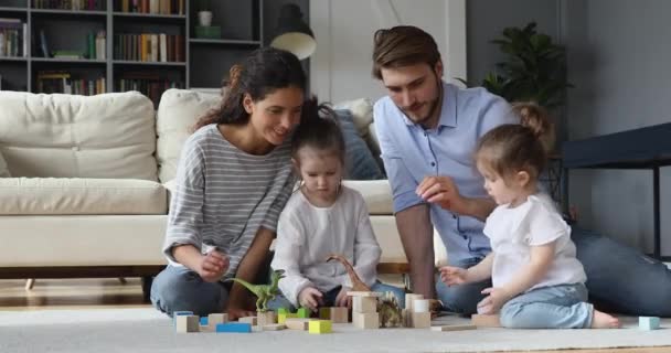 Feliz joven pareja casada jugando con niños pequeños en el suelo. — Vídeos de Stock