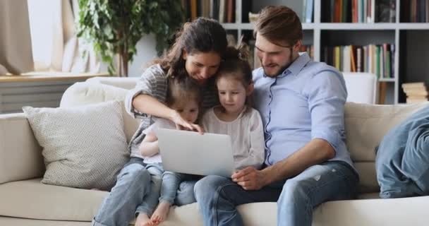 Uśmiechnięta mama i tata oglądają kreskówki z dziećmi na laptopie. — Wideo stockowe