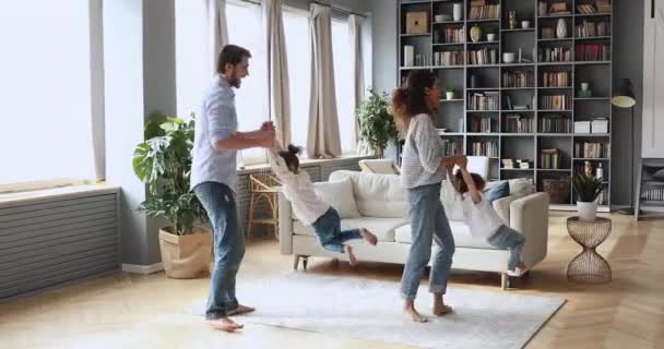 Pais felizes dançando com engraçado crianças pequenas irmãs em casa . — Vídeo de Stock