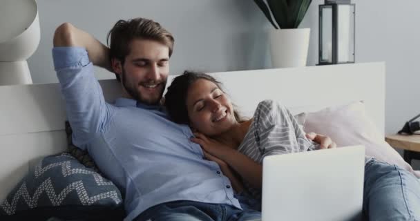 Šťastný milující manželský pár sledující vtipné filmy v ložnici. — Stock video
