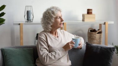 Son sınıf öğrencisi, elinde fincanla kanepede oturmuş evde dinleniyor.