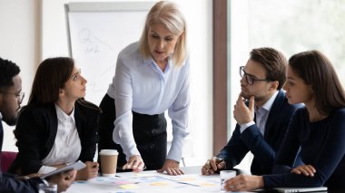 Çeşitli çalışanlar ciddi bir yetişkin koçu dinlerken atölye sırasında bilgi sağlarlar