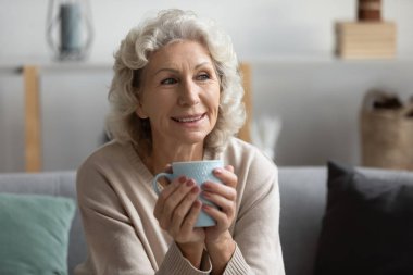 Büyükanne, kanepede otur ve bardağı tut. Evde tek başına dinleniyor.