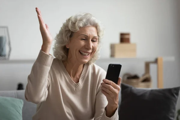 Grandmother greets grownup children enjoy distant talk by smartphone videoconference