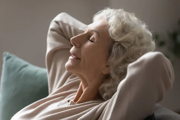 Grandmother put hands behind head relaxing on couch closeup photo — Stock Photo, Image