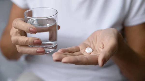 Closeup mature woman hands holding pill and glass of water — Stock Photo, Image