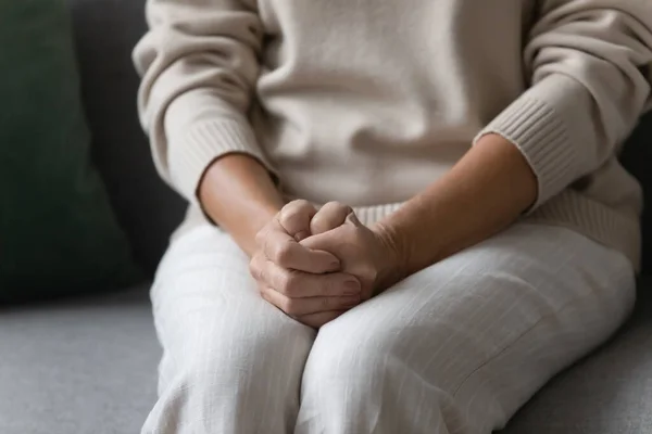 Femme âgée solitaire mettre les mains sur les tours assis sur le canapé — Photo