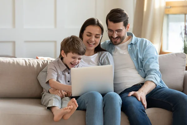 Jovem feliz usando computador com marido e criança pequena . — Fotografia de Stock