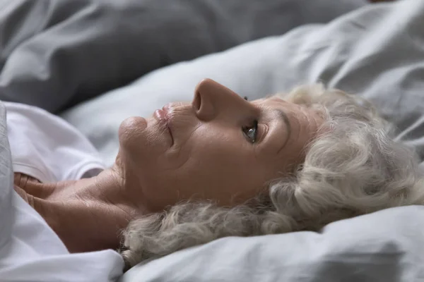 Closeup view mature woman lying on bed suffers from insomnia — Stock Photo, Image